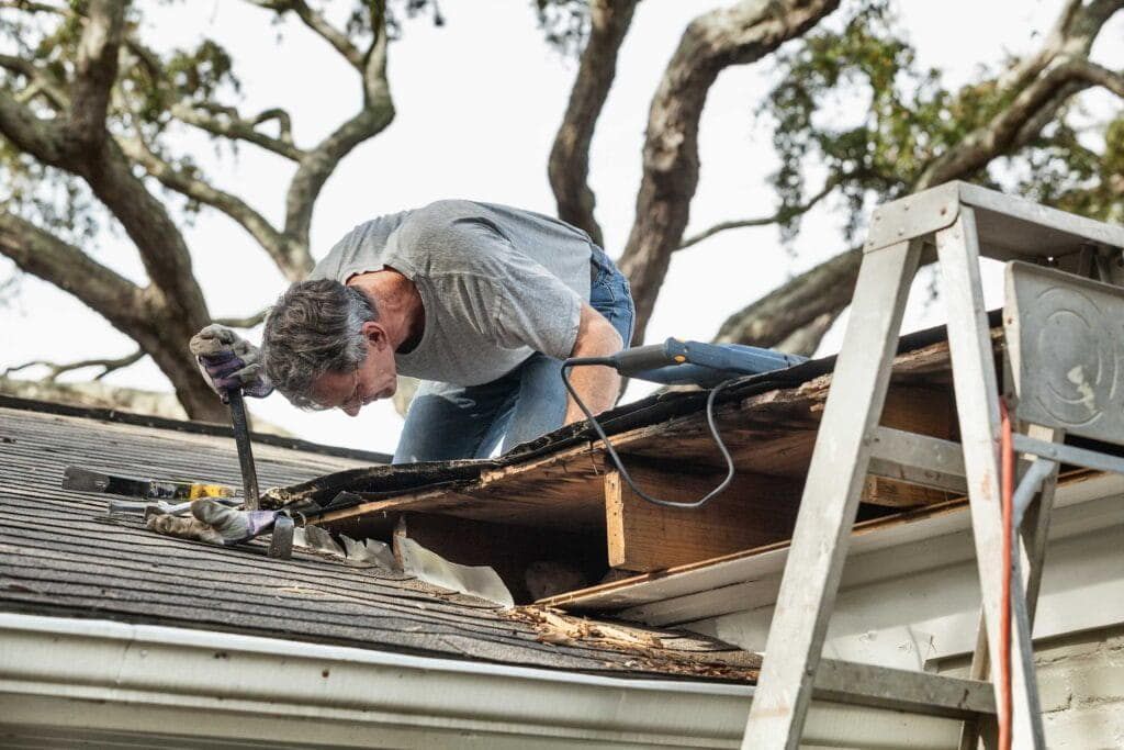 Roofer repairing storm damage at a roof edge
