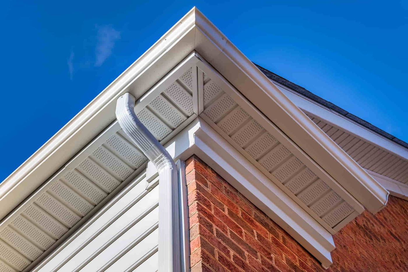 Seamless white gutter along the roofline of a brick home
