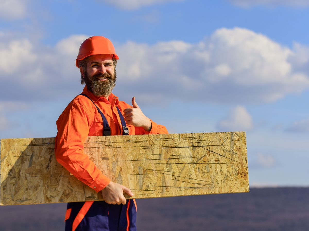Roofer smiling while holding board for architectural shingles