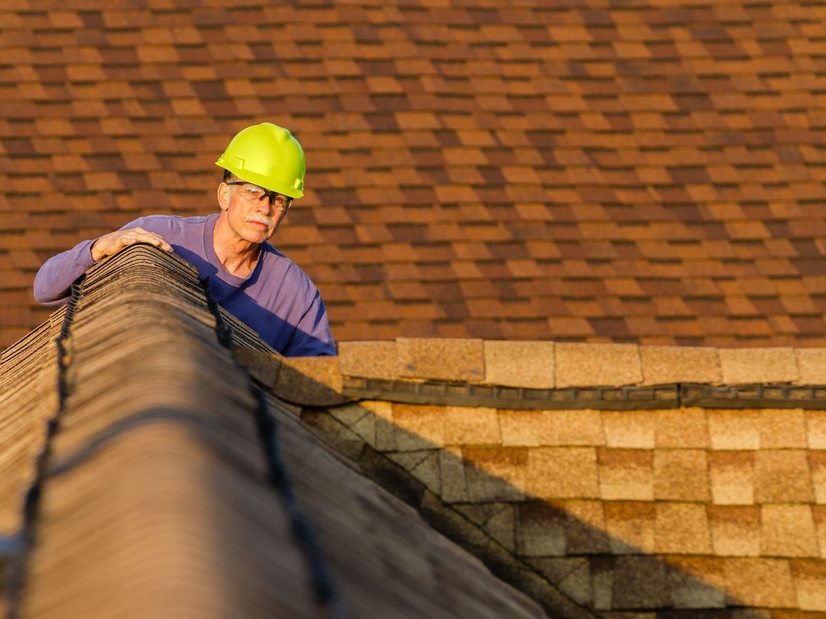 Roofer examining the roof with architectural shingles