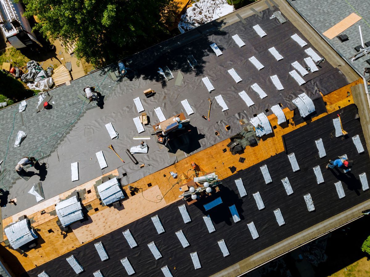 Roofers installing architectural shingles on roof deck