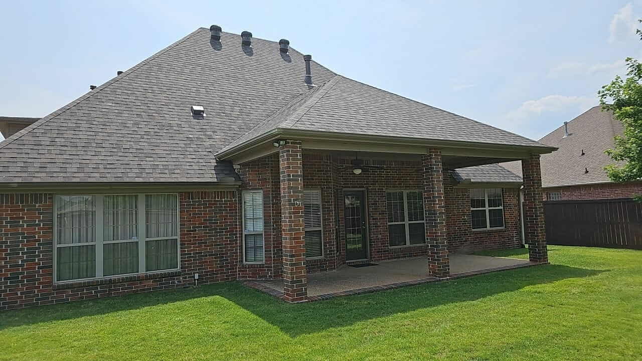 Completed roof replacement on a brick ranch home with a covered back patio