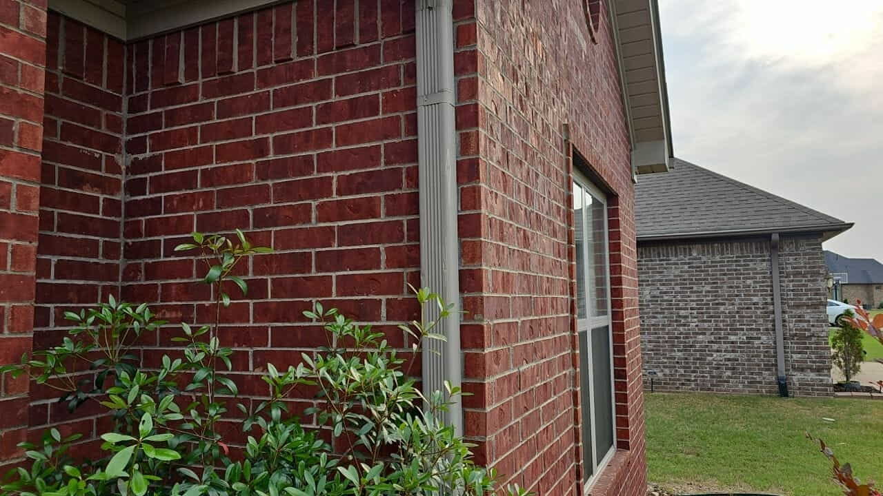 New shingle roof edge above a red brick wall